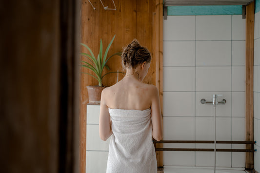 Woman wrapped in a towel in a bright, modern bathroom after a shower