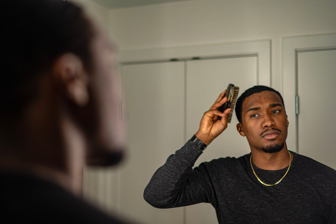 Man styling and combing his hair in a bathroom mirror during a natural morning grooming routine