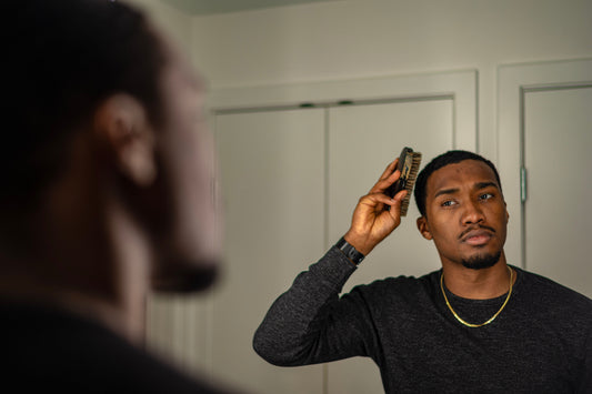 Man styling and combing his hair in a bathroom mirror during a natural morning grooming routine