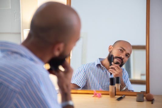 Man combing his beard while looking into a mirror