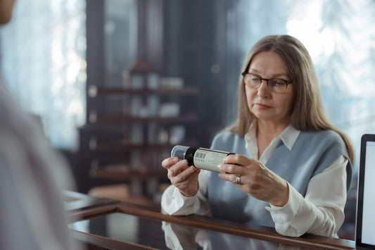 Woman thoughtfully reading a product label on a bottle indoors